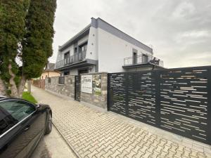 a car parked in front of a house with a fence at Ubytovanie Tereza in Veľký Meder