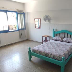 a bedroom with a green bed and two windows at rafa's house in Mendoza