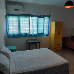 sypialnia z łóżkiem i oknem z niebieskimi zasłonami w obiekcie rafa's house w mieście Mendoza