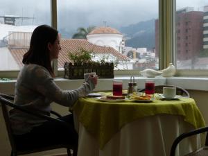 Eine Frau, die an einem Tisch mit einem Teller Essen sitzt. in der Unterkunft City Art Hotel Silberstein in Quito