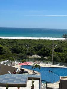 a swimming pool with a beach in the background at Praia Grande Arraial do Cabo in Arraial do Cabo