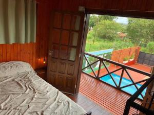 a bedroom with a bed and a balcony with a pool at Hermosa y confortable cabaña in Puerto Iguazú