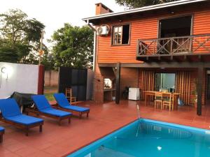 a patio with chairs and a pool in front of a house at Hermosa y confortable cabaña in Puerto Iguazú