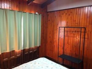 a bedroom with wooden walls and a bed and a window at Hermosa y confortable cabaña in Puerto Iguazú +25 photos