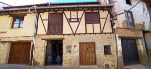 un antiguo edificio de piedra con puertas y ventanas de madera en Dúplex Ca tío Celso en San Esteban de la Sierra