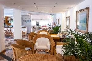 une salle d'attente avec des chaises et des tables en osier dans un magasin dans l'établissement Hotel Corallaro, à Santa Teresa Gallura