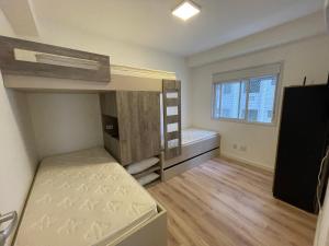 a bedroom with two bunk beds and a window at Apartamento ponta das galhetas ( praia Asturias ) in Guarujá