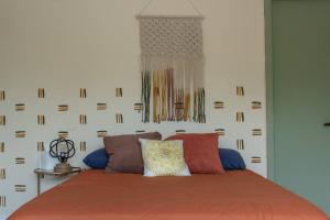 a bedroom with a bed with a orange blanket and pillows at The Green Door Bungalow in Naples