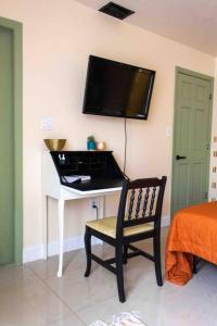 a room with a chair and a television on a wall at The Green Door Bungalow in Naples