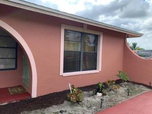a pink house with a window and some plants at The Green Door Bungalow in Naples