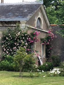 una casa vieja con flores a un lado. en Gîte La Sellerie en Les Sorinières