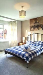 a bedroom with a blue and white checkered bed at Luxurious 4 Bedroom Detached Family Home in Burton Joyce