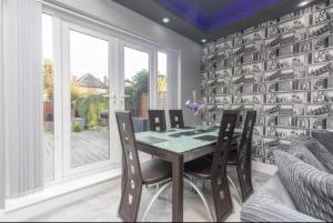 a dining room with a table and chairs and a wall with books at Luxurious 4 Bedroom Detached Family Home in Burton Joyce