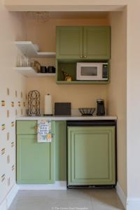 a kitchen with green cabinets and a microwave at The Green Door Bungalow in Naples