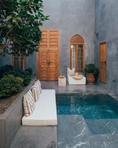 um pátio com uma piscina de água e dois bancos em Riad no37 em Marraquexe