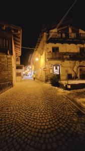 osoba idąca nocą brukowaną ulicą w obiekcie BAITA 2 LOVELY AND CENTRAL SAUZE D'OULX w mieście Sauze dʼOulx