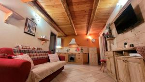 salon z czerwoną kanapą i kuchnią w obiekcie BAITA 2 LOVELY AND CENTRAL SAUZE D'OULX w mieście Sauze dʼOulx