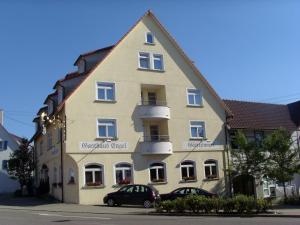a large yellow building with a car parked in front of it at Hotel & Restaurant Engel in Herbertingen