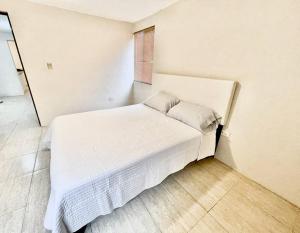 - un lit blanc dans une chambre blanche dotée d'une fenêtre dans l'établissement Acogedor departamento 3 recamaras, à Reynosa