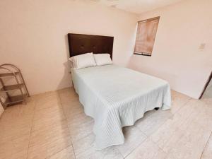 Un dormitorio con una cama con una manta blanca. en Acogedor departamento 3 recamaras, en Reynosa