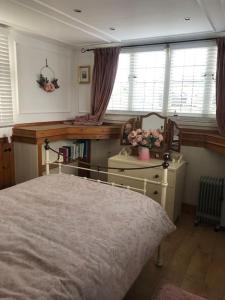 a bedroom with a bed and a desk and windows at Toosey Lass - St Osyth creek in Saint Osyth