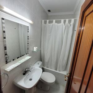 a white bathroom with a toilet and a sink at Hostal Pan America in Madrid +9 photos