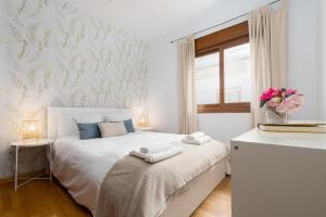 ein weißes Schlafzimmer mit einem Bett mit einer Blumenvase in der Unterkunft AGUA 21 in Málaga