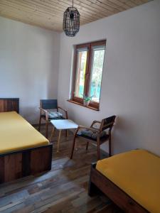 um quarto com 2 camas e cadeiras e uma janela em Domki Pod Lasem em Ostrowo