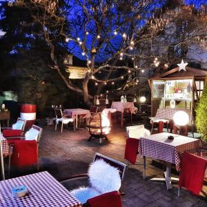 eine Terrasse mit Tischen und Stühlen und ein Baum mit Lichtern in der Unterkunft Hotel Restaurant Aux Sapins in Thann