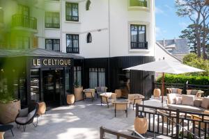 un patio avec des tables et des chaises en face d'un bâtiment dans l'établissement Le Celtique & Spa, à Carnac