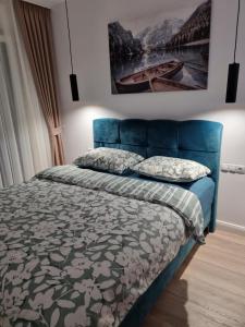 una camera da letto con un letto blu e un dipinto sul muro di Roxana Residence a Oradea