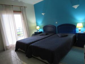 1 dormitorio azul con 2 camas y ventana en Hotel Apartamento Praia Azul, en Silveira
