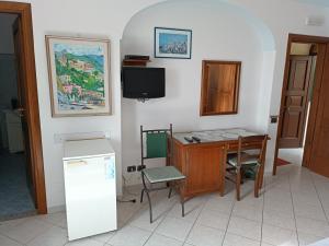 Zimmer mit einem Schreibtisch, einem TV und einem Tisch in der Unterkunft NINO'S IN NOCELLE in Positano