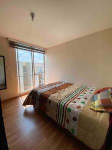 1 dormitorio con cama y ventana grande en Hermoso departamento en Cuautlancingo, en Santa María Coronanco