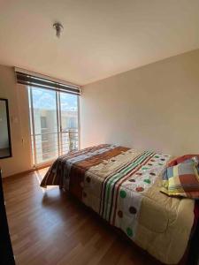 a bedroom with a bed and a large window at Hermoso departamento en Cuautlancingo in Santa María Coronanco