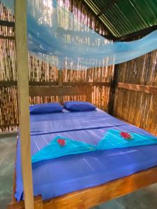 a bed in a straw hut with blue sheets at Hostal Mirador Mar Nevado in Buritaca