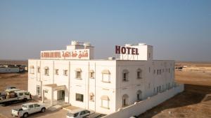 a hotel in the desert with cars parked in front of it at Al Ghaba Line Hotel in Al Ghābah