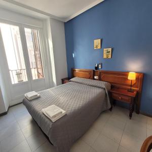 1 dormitorio con cama y pared azul en Hostal Pan America, en Madrid