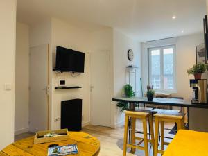 a living room with a table and a tv on the wall at Le Duplex 3 chambres - 1P à 7P - Saint Honore in Amiens