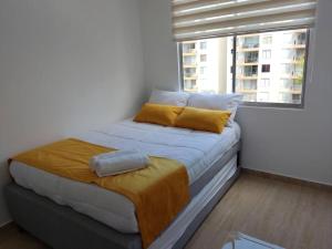 1 cama con almohadas amarillas en una habitación con ventana en Apartamento en Hacienda Peñalisa Ceiba, Sol, Piscina y descanso, en Girardot