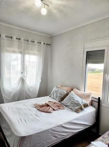 a bed in a bedroom with a window with white curtains at ALEX HOUSE in Nea Potidaea