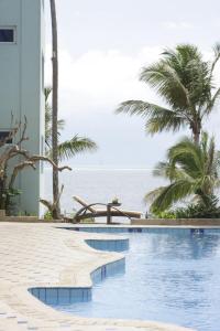 a swimming pool with the ocean in the background at Cowrie Shell Beach Apartments Official in Bamburi
