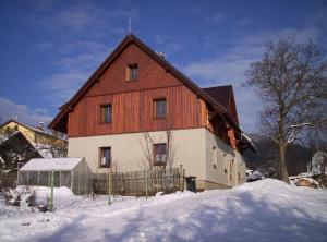 duża drewniana stodoła w śniegu w obiekcie Apartments Anna w mieście Cerny Dul