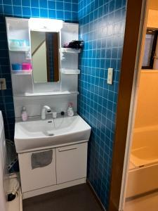 a bathroom with a sink and a mirror and blue tiles at 舟荘 in Osaka
