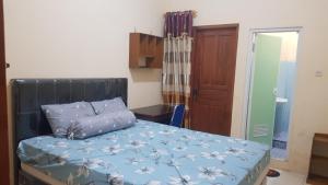 a bedroom with a bed with a blue comforter at Guest House GRIYA THAMRIN SYARIAH in Bonorejo