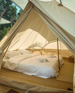 a bed in a canvas tent with clothes on it at GO GLAMPING MAEPIM CAPE in Ban Nam Lai Ta Tum