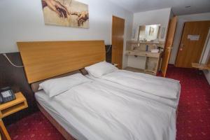Schlafzimmer mit einem großen Bett mit einem Kopfteil aus Holz in der Unterkunft City Hotel in Brunnen