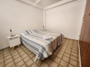 1 dormitorio con 1 cama con manta a rayas y mesita de noche en DPTO BALCARCE en Salta