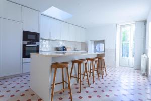a kitchen with white cabinets and bar stools at The Palace Penthouse in Porto