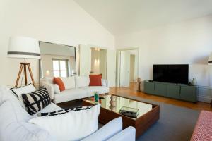 a living room with two white couches and a tv at The Palace Penthouse in Porto